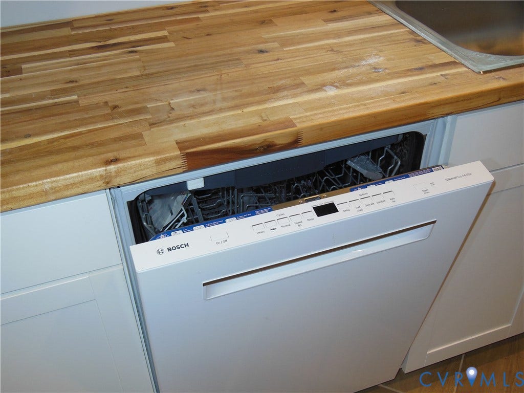 Wood-finish countertop with an integrated stainless steel sink and a white Bosch dishwasher