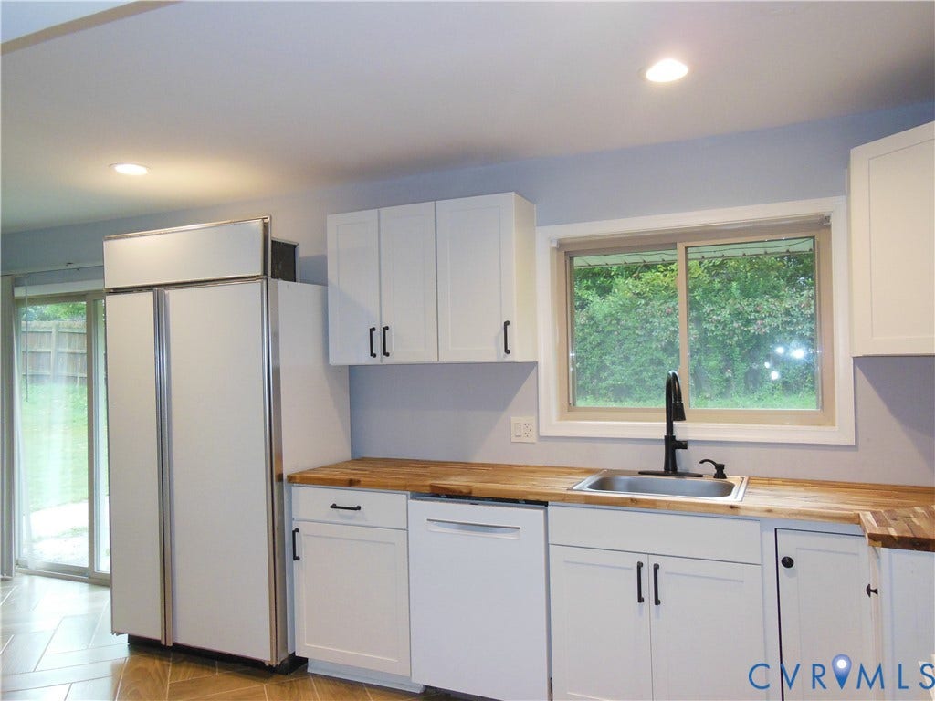 White shaker cabinetry, wood-finish countertops, stainless steel sink, black gooseneck faucet, and recessed lighting