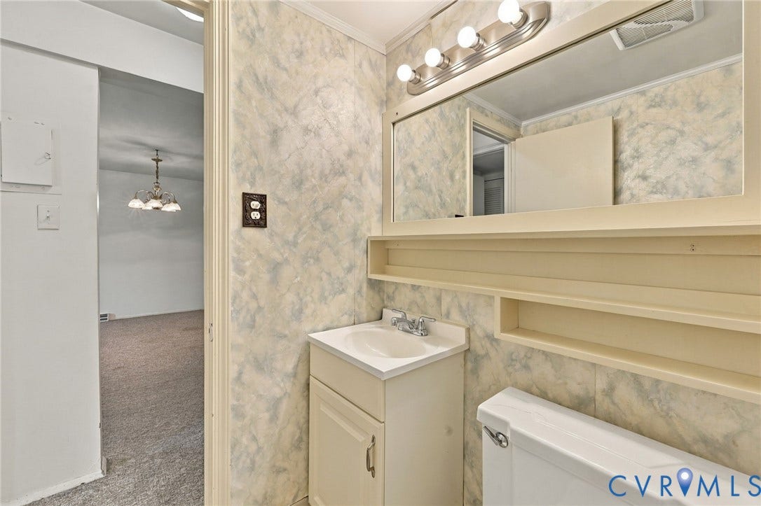 12 Snughaven Road, Hamlet, Henrico, VA 23228 Vanity with integrated sink, wall-mounted mirror, light fixture with multiple bulbs, built-in shelving, and toilet