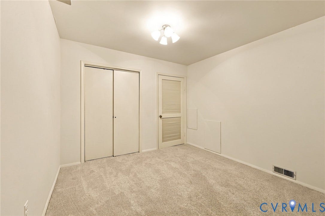 12 Snughaven Road, Hamlet, Henrico, VA 23228 Neutral-toned walls with light-colored carpeting, a ceiling-mounted light fixture, and a two-panel sliding closet door