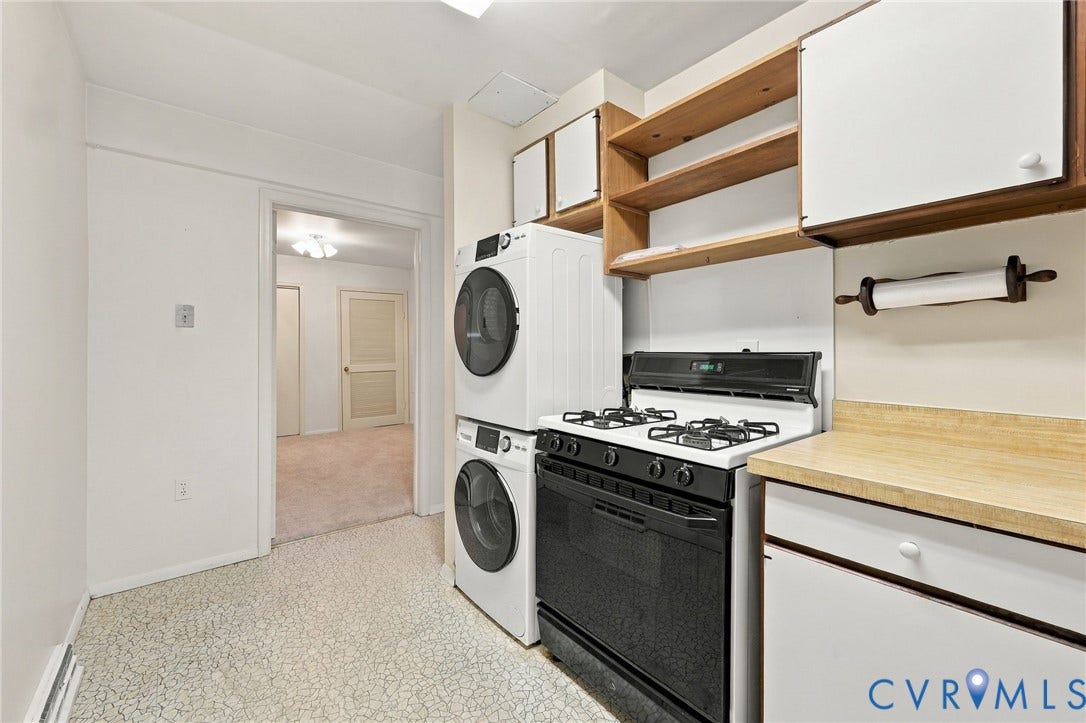 12 Snughaven Road, Hamlet, Henrico, VA 23228 White and black gas range, stacked washer and dryer, wood-finish open shelving, and white cabinetry with wood trim