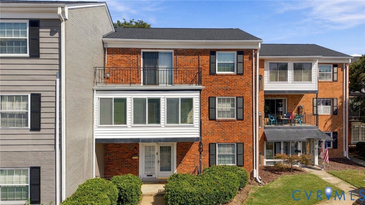 12 Snughaven Road, Hamlet, Henrico, VA 23228 Brick exterior featuring multiple windows with black shutters, a second-story balcony with metal railings, and a covered entry