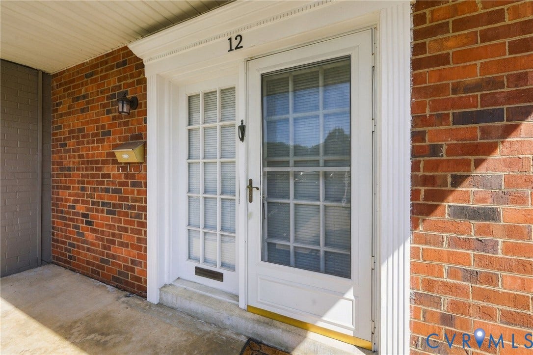 12 Snughaven Road, Hamlet, Henrico, VA 23228 Brick exterior with white trim, a decorative entry door frame, and a screen door with grilles