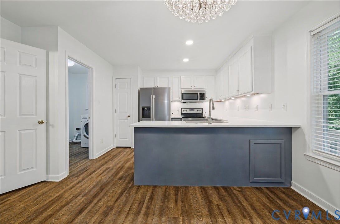 15724 Winding Ash Drive, Chesterfield, VA 23832 Kitchen featuring stainless steel appliances, white cabinetry, a built-in island with contrasting blue paneling, wood-finish flooring, and a crystal chandelier