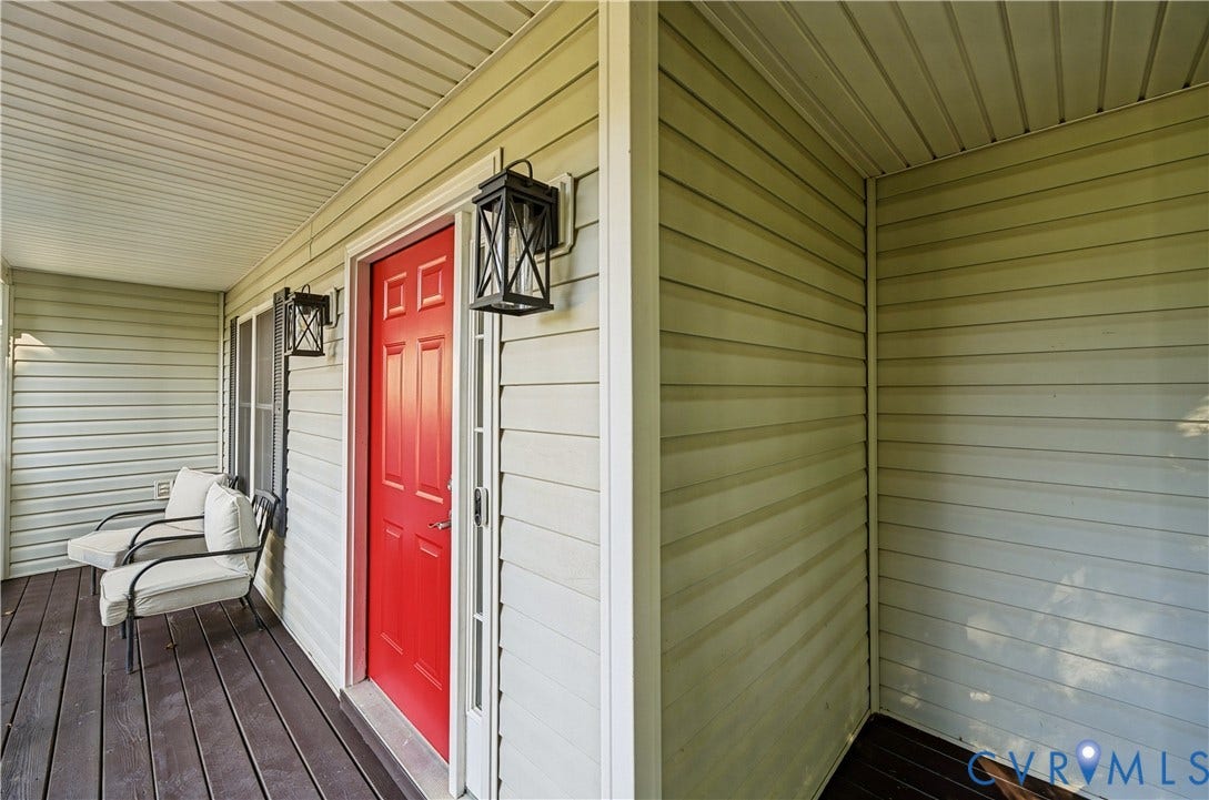 15724 Winding Ash Drive, Chesterfield, VA 23832 Covered porch featuring a paneled red entry door, two exterior wall lanterns, and horizontal siding
