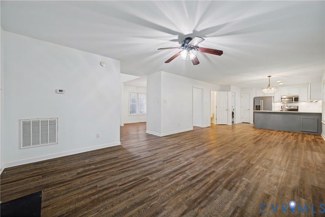 15724 Winding Ash Drive, Chesterfield, VA 23832 Open concept living space featuring wood-finish flooring, a ceiling fan, and a kitchen with stainless steel appliances, white cabinetry, and a crystal chandelier