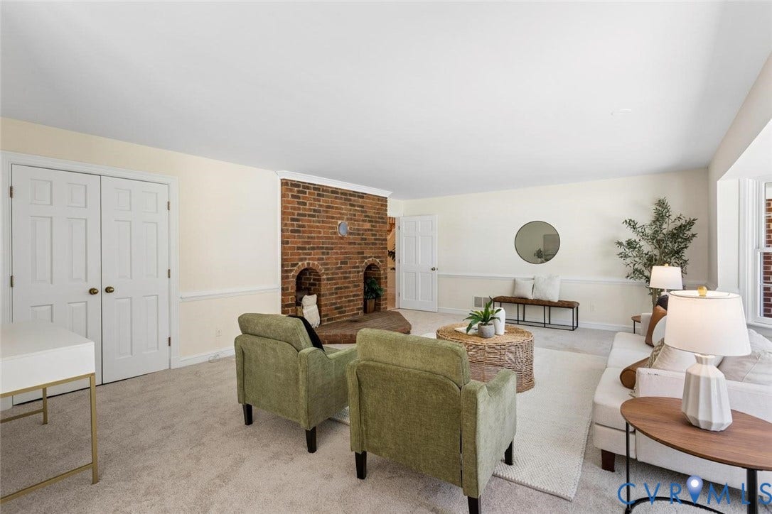 Brick-clad fireplace with arched openings, neutral carpet flooring, white paneled double doors, and a bay window