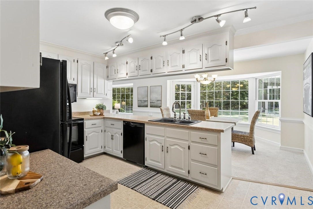 White cabinetry with black appliances, track lighting, and a kitchen island with a double basin sink
