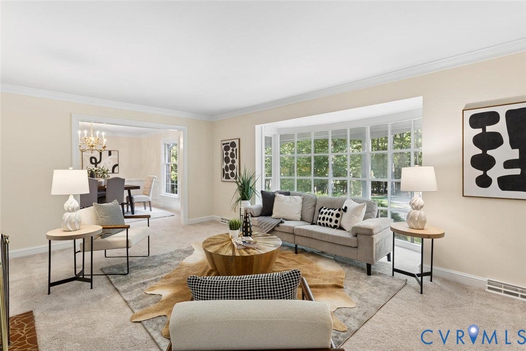 Expansive living area featuring a large bay window, neutral carpeting, and crown molding