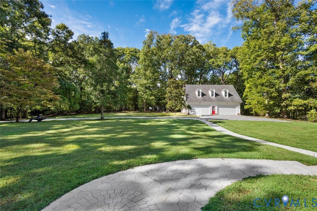 Detached garage with three dormer windows, a gravel driveway, and a paved walkway