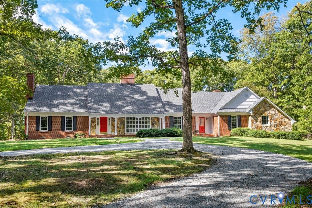 Brick and stone exterior with a shingle roof, featuring multiple front entryways and a gravel driveway