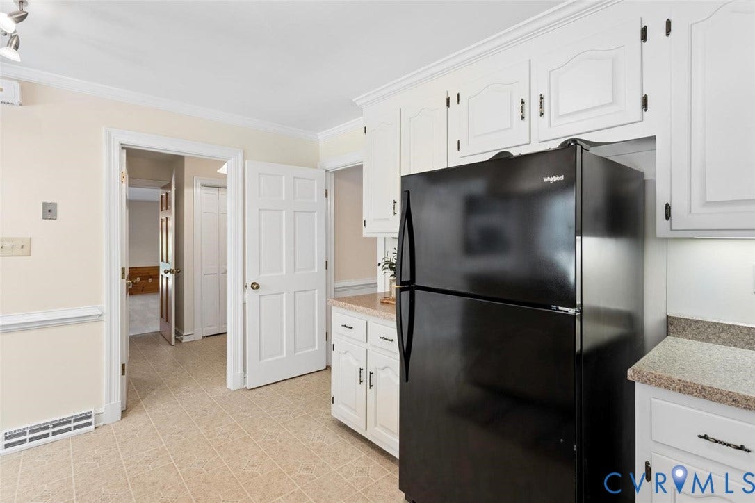 White cabinetry with dark hardware, stone-finish countertops, and vinyl flooring
