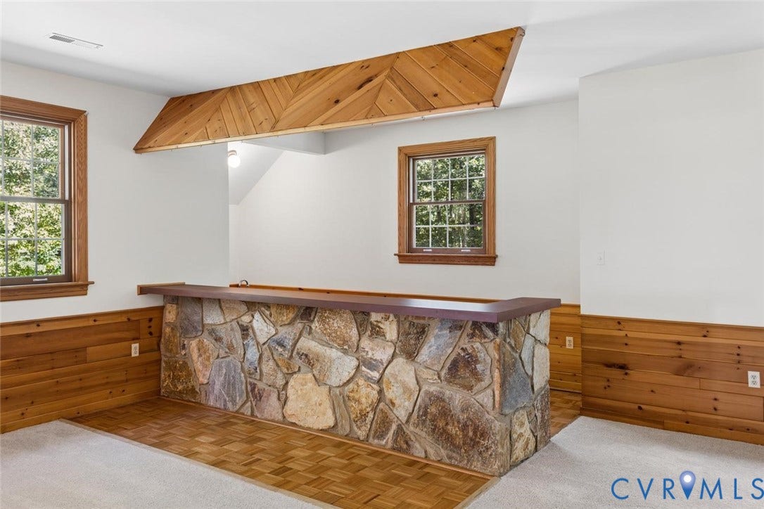 Stone-clad bar with a wood-finish countertop, complemented by wood-paneled walls, and wood-finish window frames