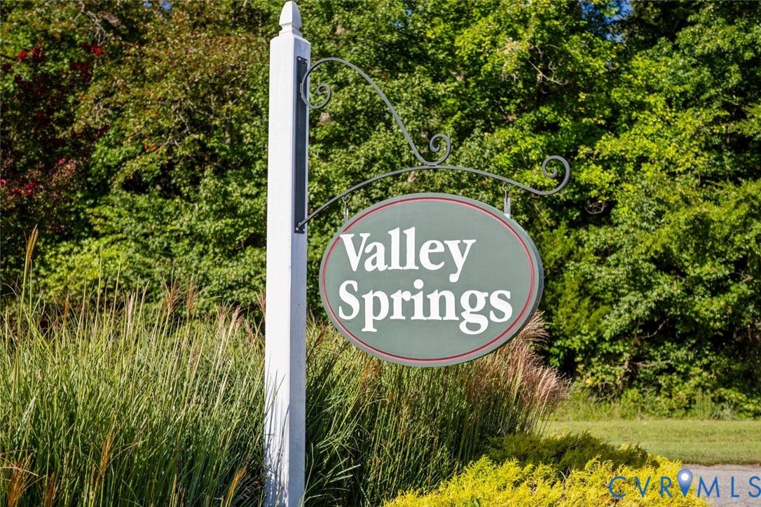 Community entry sign with a white post and dark green oval signage