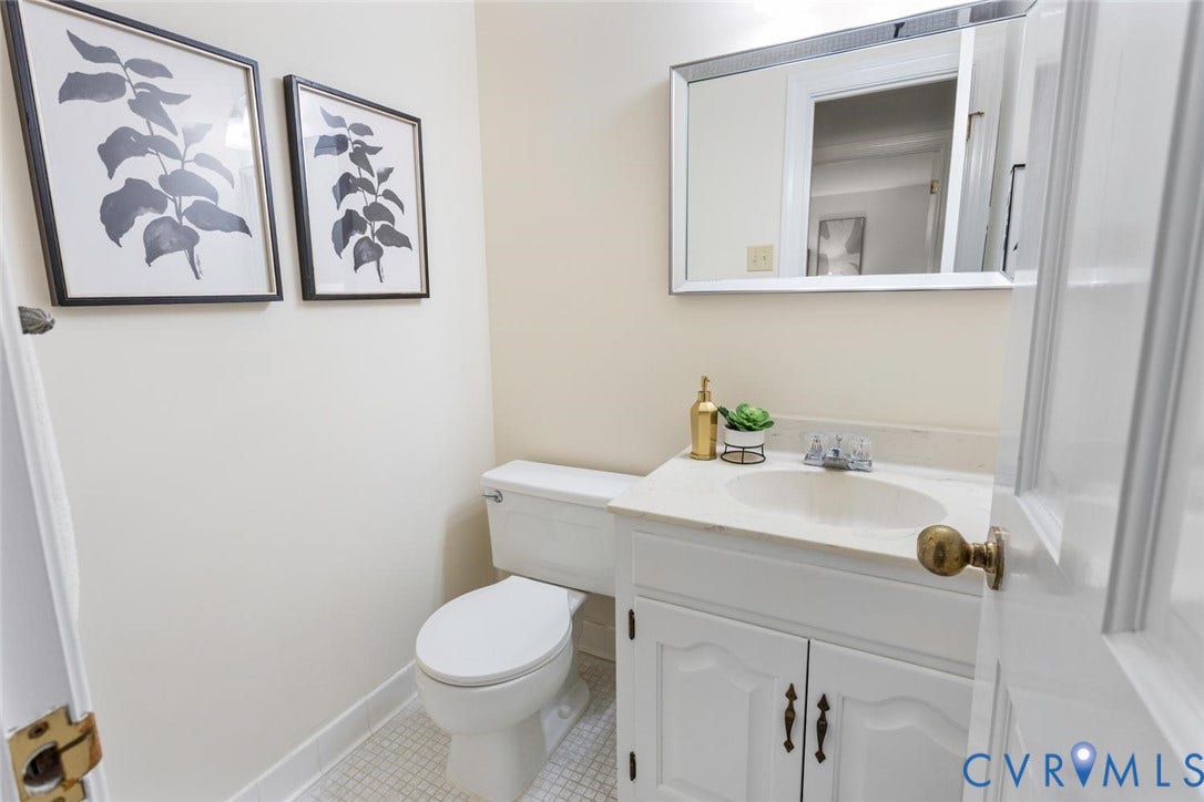White vanity with cabinet storage, integrated sink, and wall-mounted mirror