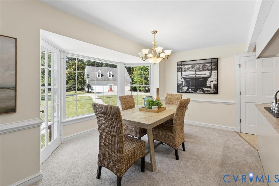 Bay window with French doors, brass chandelier, crown molding, chair rail, and carpeted flooring
