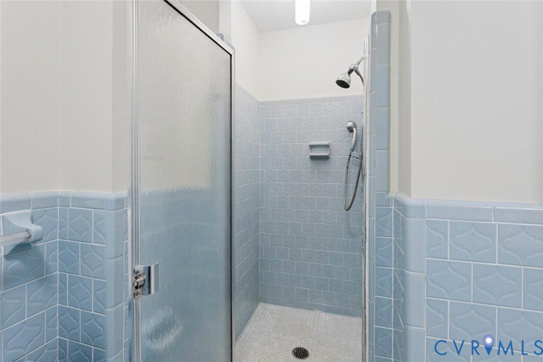 Shower stall with a glass enclosure, blue patterned wall tile, and a tile shower floor