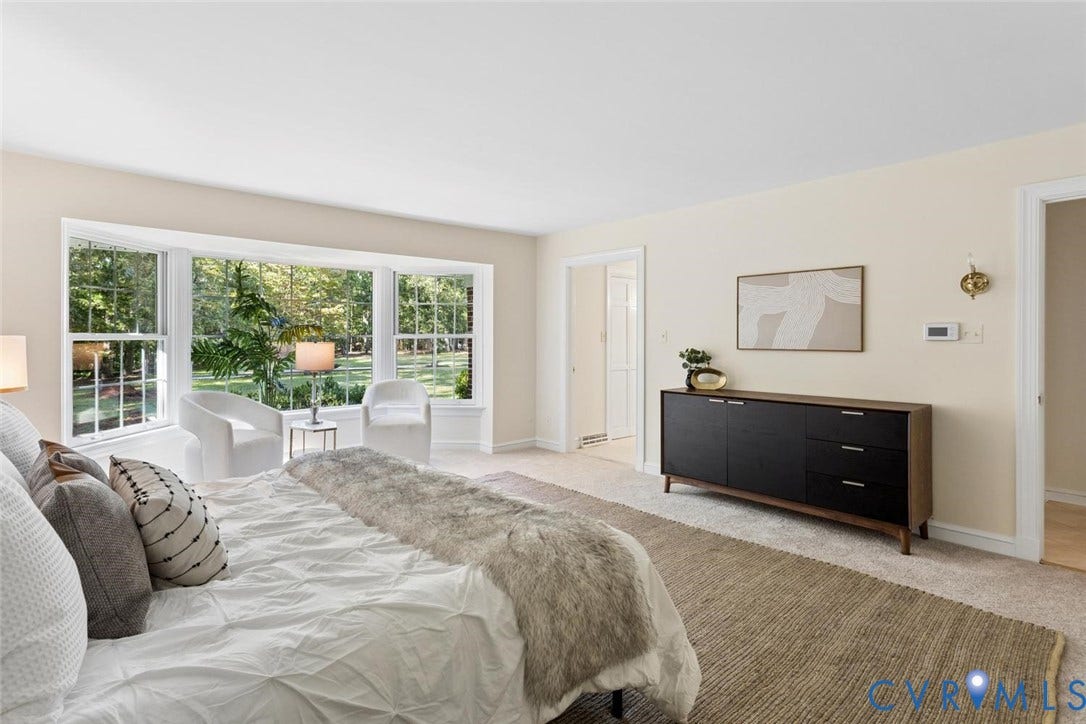 Expansive bay window, neutral wall tones, and plush carpeting