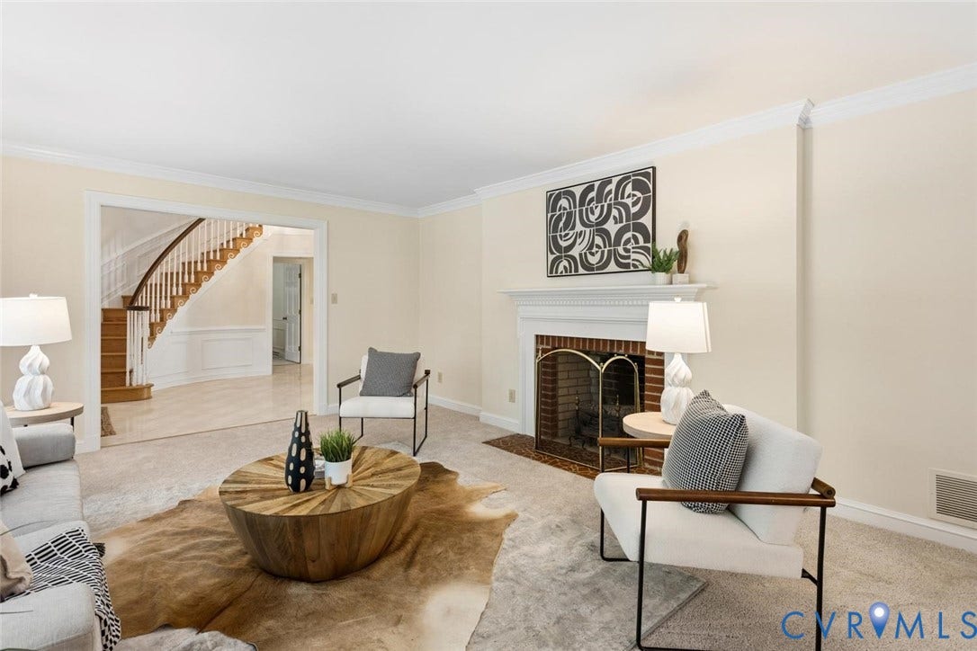 Formal living space featuring carpet flooring and a fireplace with a brick surround and decorative mantel