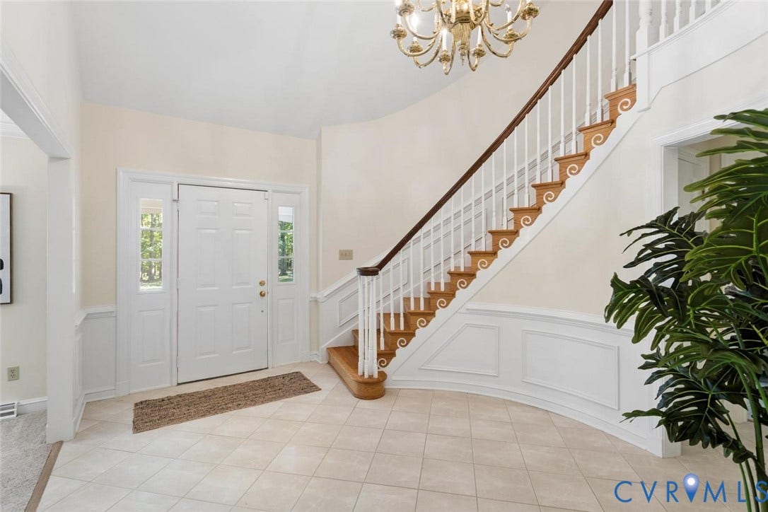 Foyer featuring a grand staircase with wood treads and white risers, decorative wainscoting, and a tiled floor