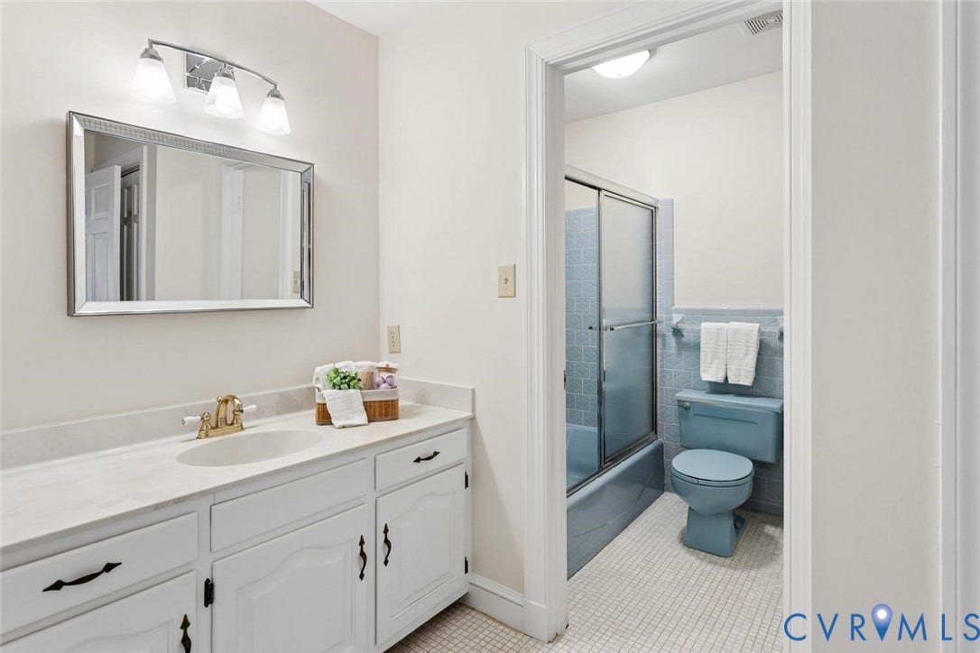Vanity with a single basin, white cabinetry, and polished countertop