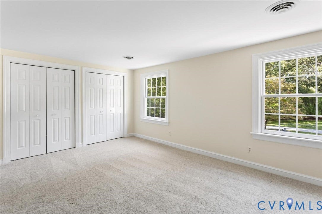 Light beige wall paint, two paneled bi-fold closet doors, two multi-pane windows, light neutral carpeting