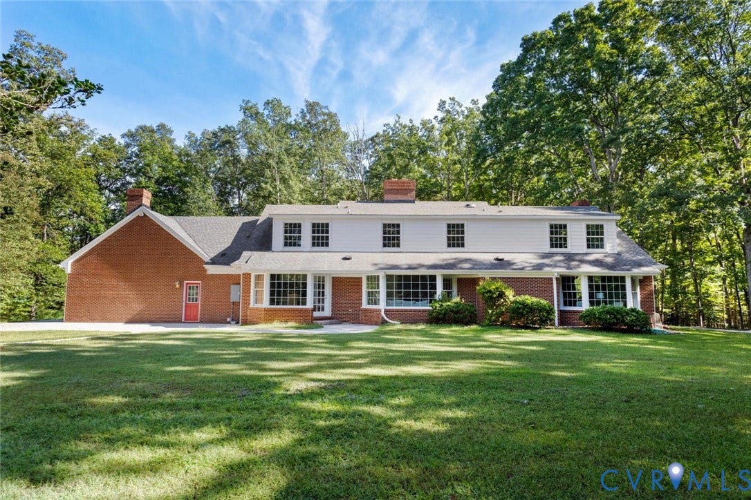 Expansive rear facade featuring brick and siding construction, multiple dormer windows, and a full-length sunroom