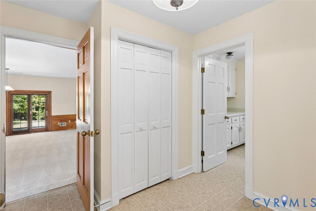 Neutral-toned tile flooring, solid wood panel door, white bi-fold closet doors, sliding glass doors, white shaker-style cabinetry