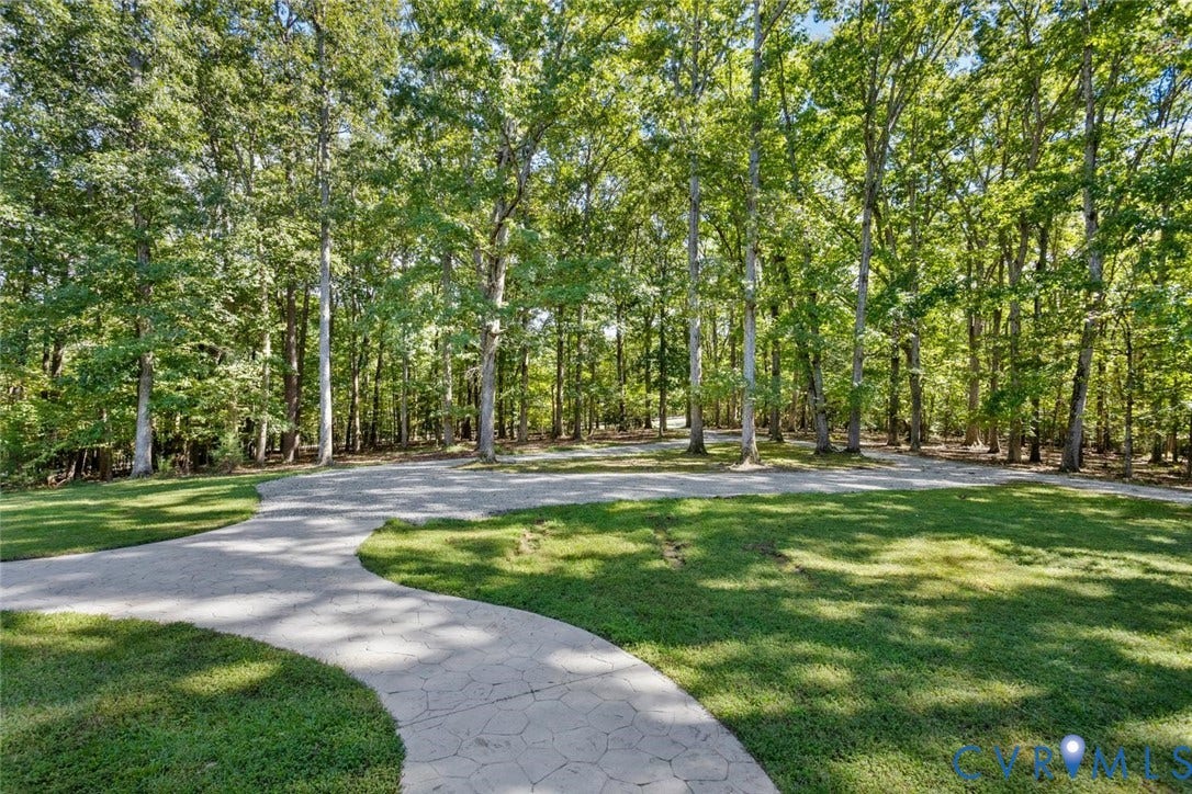 Mature trees line a curved driveway and expansive lawn