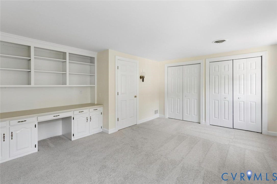 Built-in white cabinetry with desk, open shelving, and two sets of bi-fold closet doors