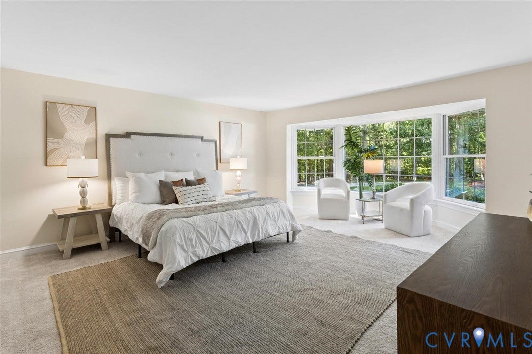 Expansive room featuring a large bay window, neutral wall tones, and carpet flooring