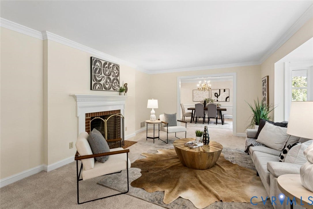 Carpeted living area featuring a white mantel fireplace with a brick firebox and brass screen