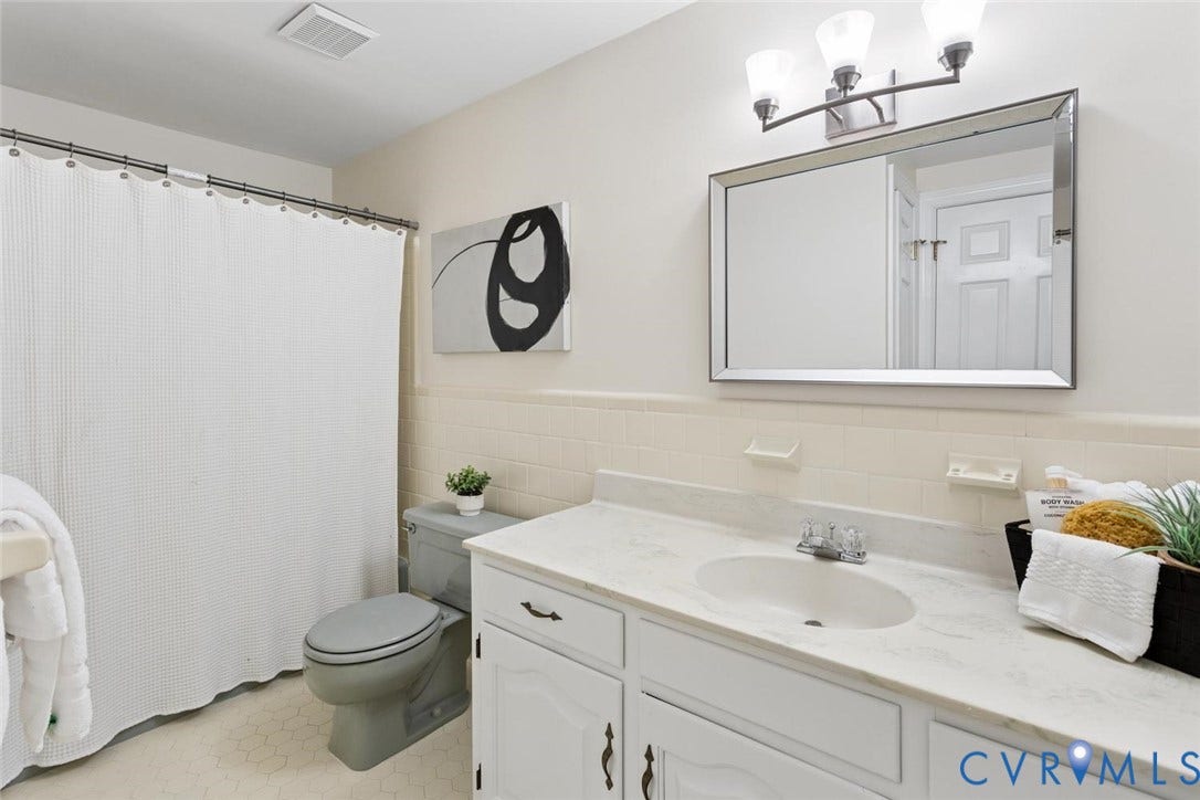 White vanity with dual cabinet doors, integrated sink, and stone-finish countertop