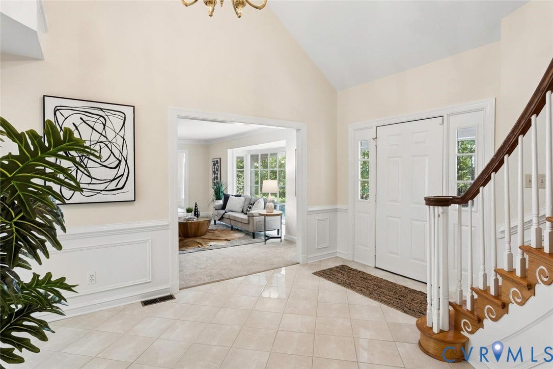 Two-story foyer with vaulted ceiling, tile flooring, wainscoting, and a white paneled entry door with sidelights