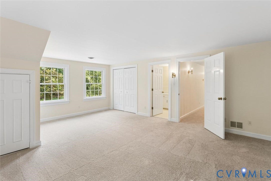 Carpeted room featuring multiple windows, white paneled doors, and wall sconce lighting