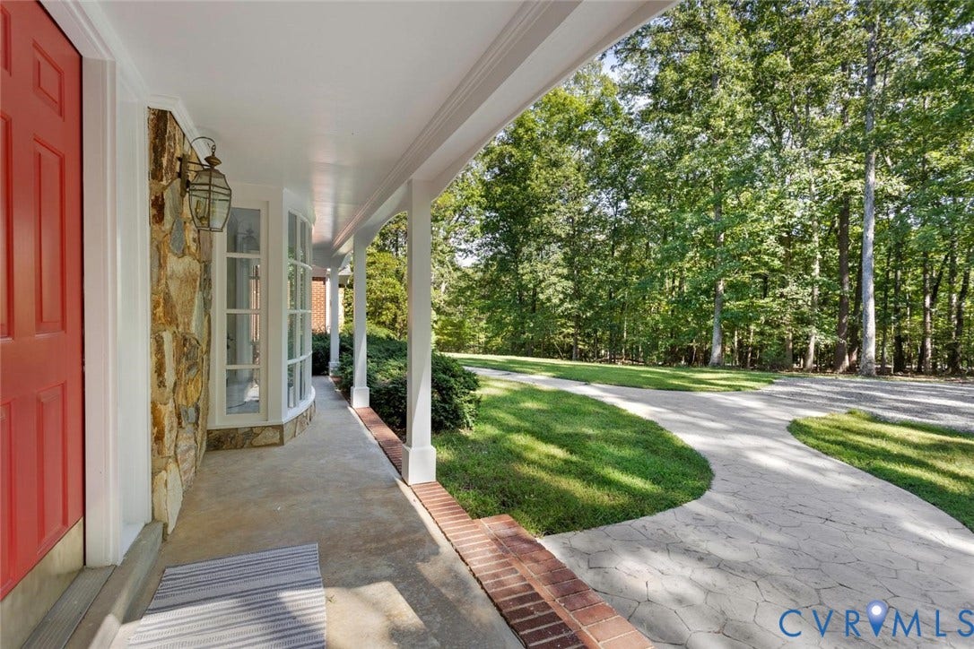 Covered front porch with stone exterior, bay window, and a lantern-style sconce