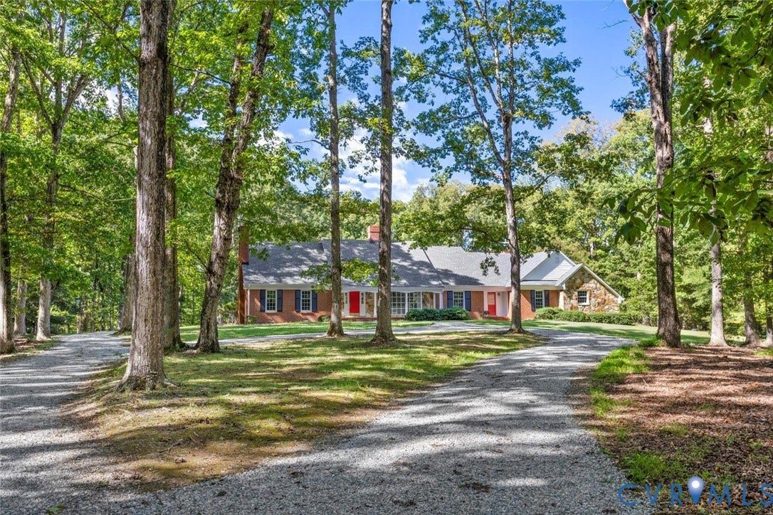 Brick and stone exterior with a gray shingle roof, surrounded by mature trees