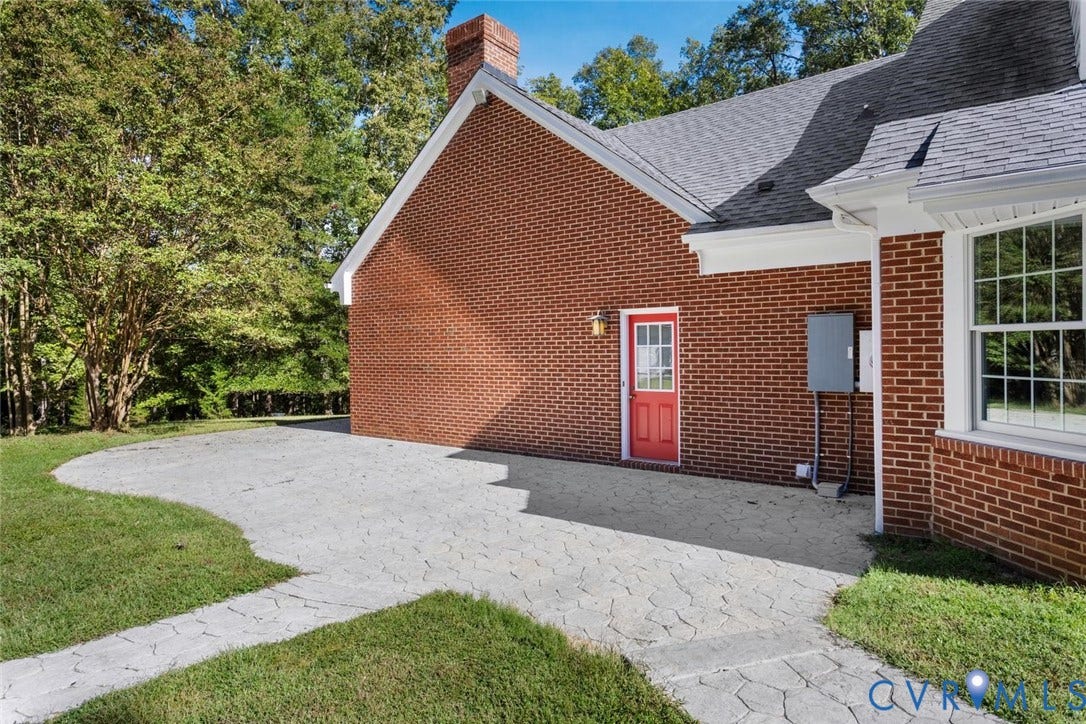 Brick exterior with a red entry door, white trim, and a shingled roof