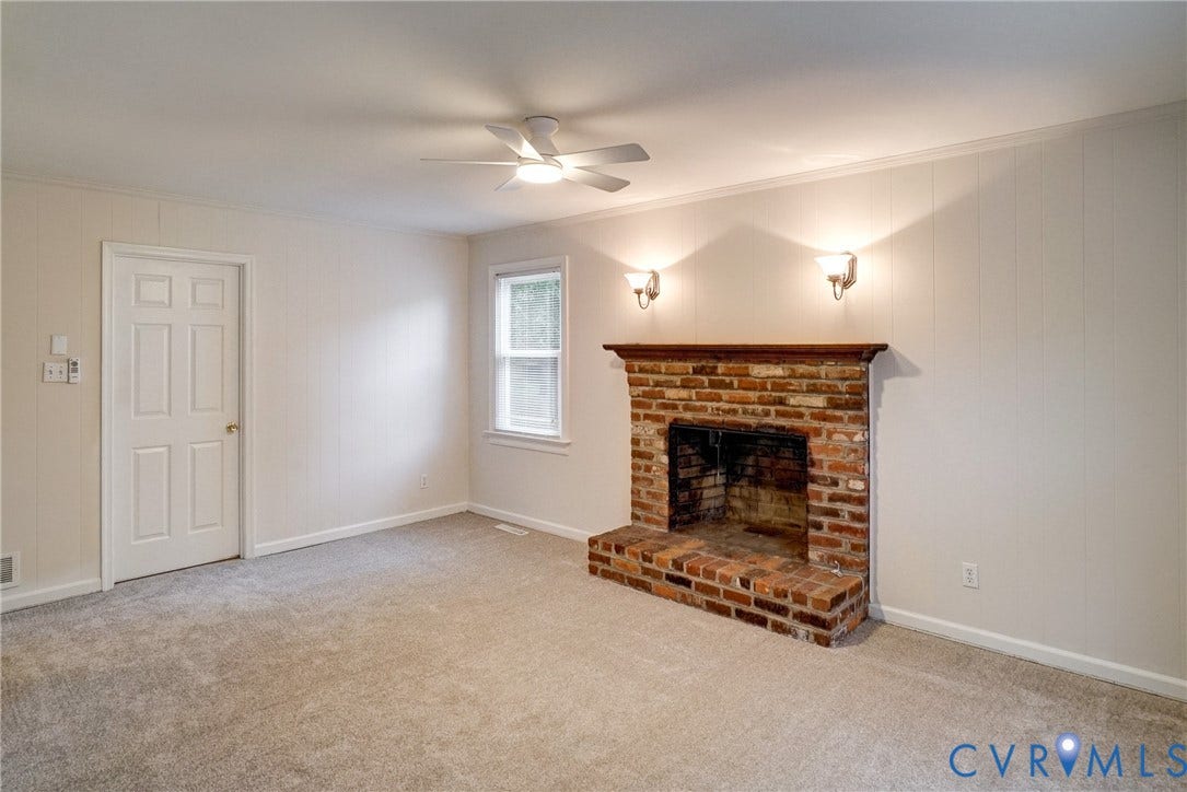 2602 Seacliff Court, Richmond, VA 23236 Brick fireplace with a wood mantel, overhead ceiling fan, and sconce lighting