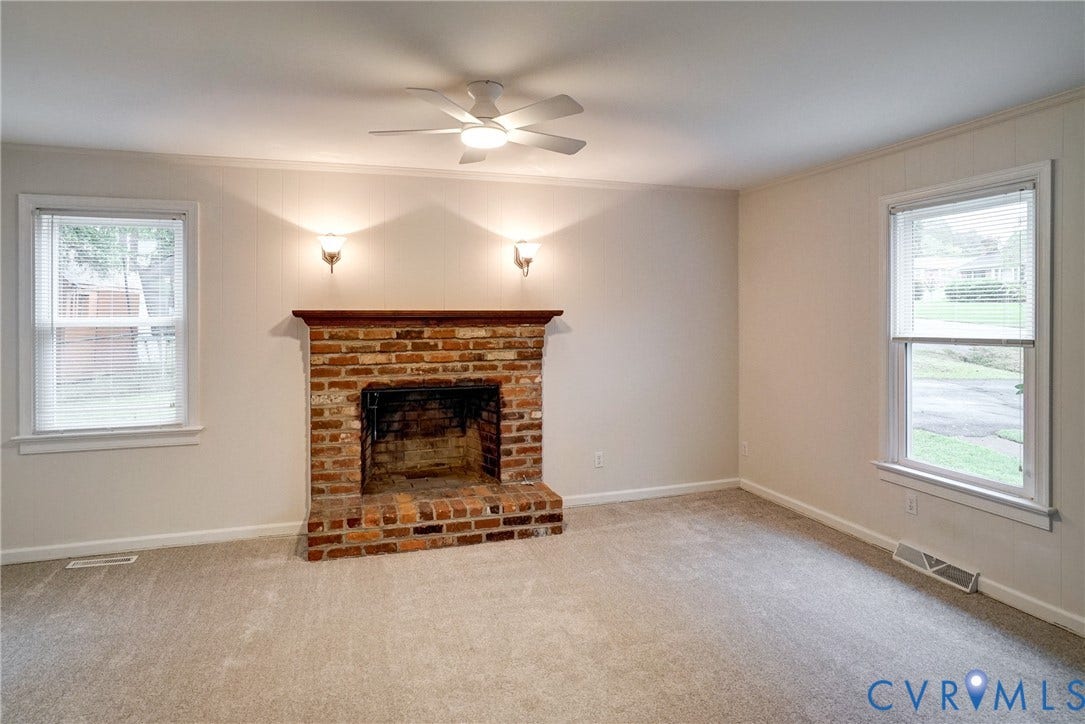2602 Seacliff Court, Richmond, VA 23236 Brick fireplace with wood mantel, wall sconces, ceiling fan with integrated lighting, and neutral carpeting