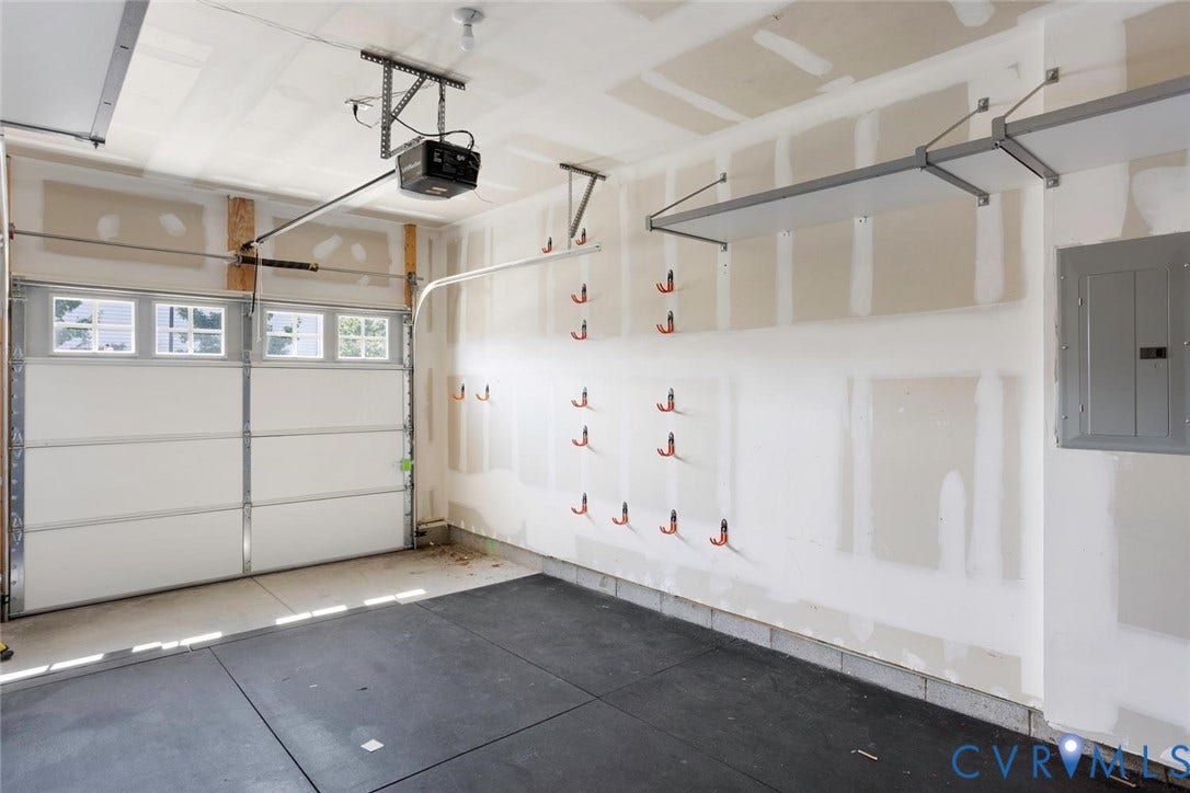 10420 Perennial Drive, Ridgefield Green Townhome, Henrico, VA 23233 Garage space featuring an automatic overhead door, overhead storage racks, integrated wall hooks, and a rubberized floor surface