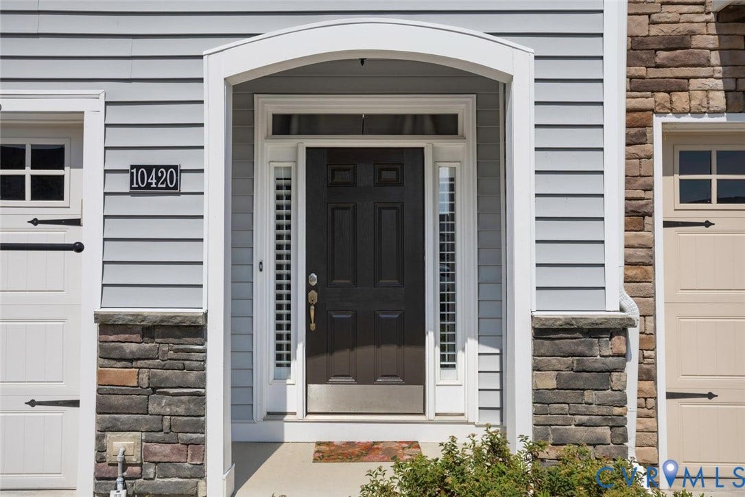 10420 Perennial Drive, Ridgefield Green Townhome, Henrico, VA 23233 Entry featuring a dark panel door with sidelights, an arched portico, light gray siding, and stone accents