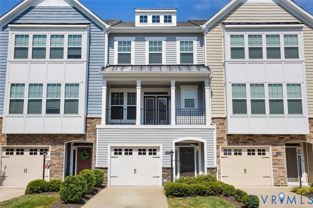 10420 Perennial Drive, Ridgefield Green Townhome, Henrico, VA 23233 Multi-level townhouse exterior featuring light-toned siding, stone accents, multiple large windows, and a covered balcony