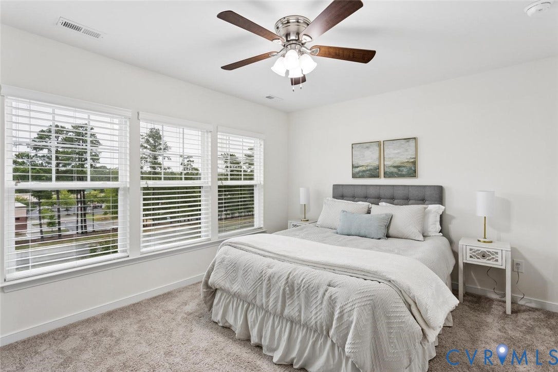 10420 Perennial Drive, Ridgefield Green Townhome, Henrico, VA 23233 Bright room featuring three double-hung windows with blinds, plush gray carpeting, and a ceiling fan with light fixture