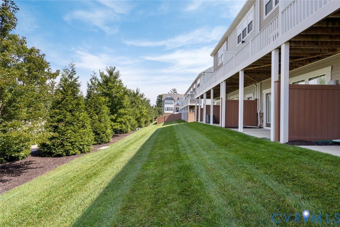 10420 Perennial Drive, Ridgefield Green Townhome, Henrico, VA 23233 Expansive outdoor space featuring a well-maintained lawn, mature trees, and private patios with brown privacy screens