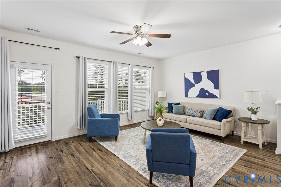 10420 Perennial Drive, Ridgefield Green Townhome, Henrico, VA 23233 Living area featuring wood-finish flooring, a ceiling fan, a white door leading to an exterior balcony, and multiple windows with blinds