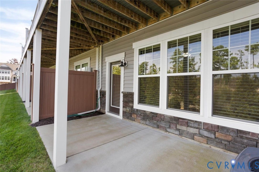 10420 Perennial Drive, Ridgefield Green Townhome, Henrico, VA 23233 Ground-level patio with stone veneer skirting, multiple windows, and a glass-paneled door
