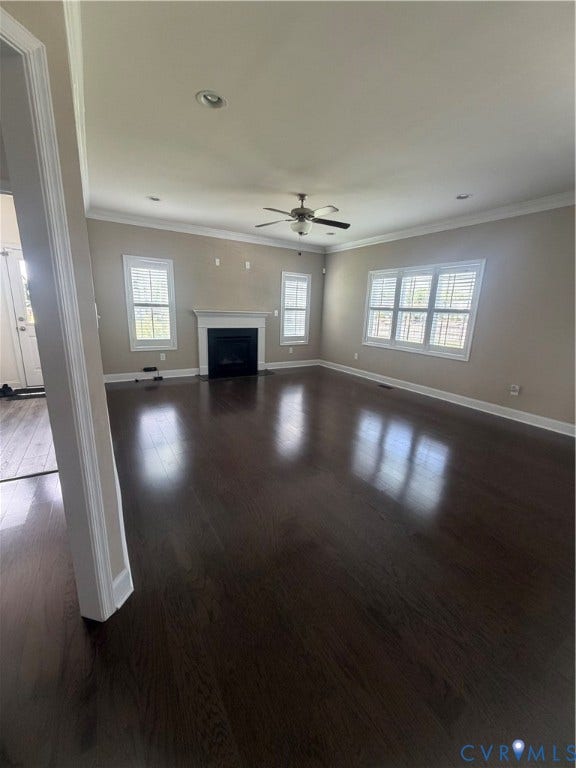 12146 Elnora Lane, Glen Allen, VA 23059 Spacious living area featuring dark wood-finish flooring, a central fireplace with a white mantel, multiple windows with white plantation shutters, a ceiling fan with integrated lighting, and recessed lighting
