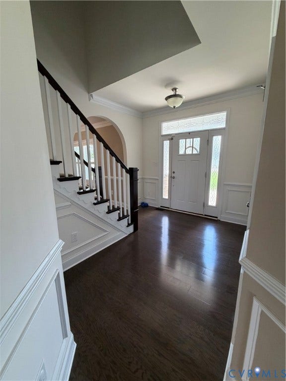 12146 Elnora Lane, Glen Allen, VA 23059 Rich wood-finish flooring, white paneled wainscoting, white double front door with sidelights and transom, staircase with dark wood-finish handrail and white balusters, and an arched doorway