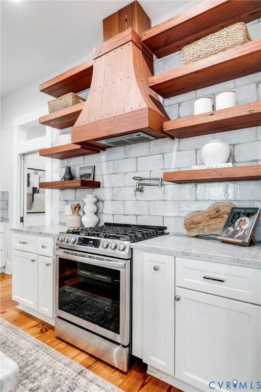 1416 Oakwood Avenue, Church Hill, Richmond, VA 23223 Stainless steel gas range with a custom wood hood, light gray subway tile backsplash, light-toned wood-finish open shelving, and white cabinetry with light-colored countertops
